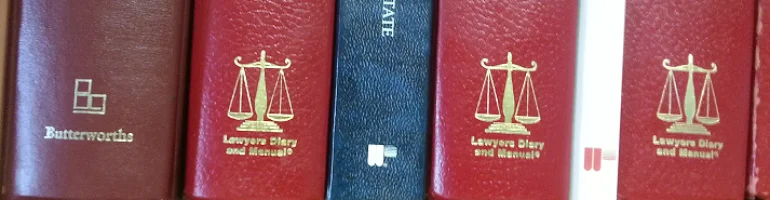 Shelf of bound law books with gold scales of justice